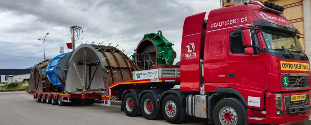 Loading heavy machinery onto lowbed trailer in industrial yard